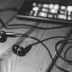 Black and white photo of earphones on a wooden table.