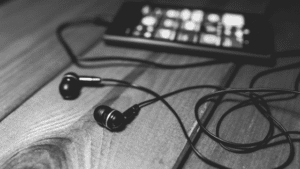 Black and white photo of earphones on a wooden table.