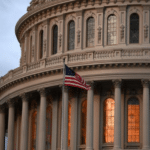 An american flag flies in front of the capitol building.