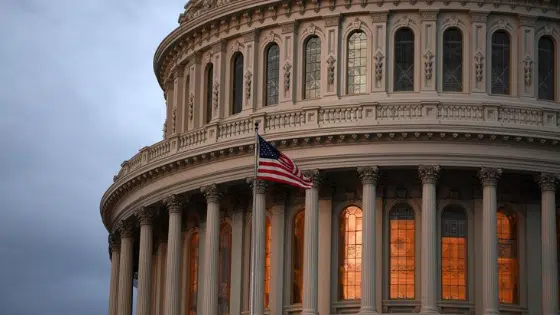 An american flag flies in front of the capitol building.