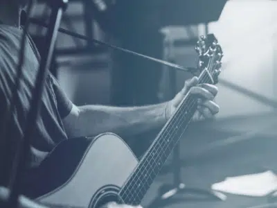 A man playing an acoustic guitar in front of a microphone.