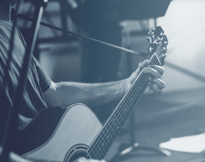 A man playing an acoustic guitar in front of a microphone.