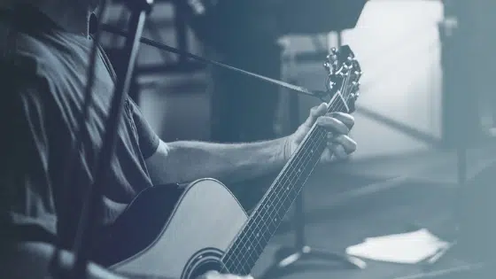 A man playing an acoustic guitar in front of a microphone.