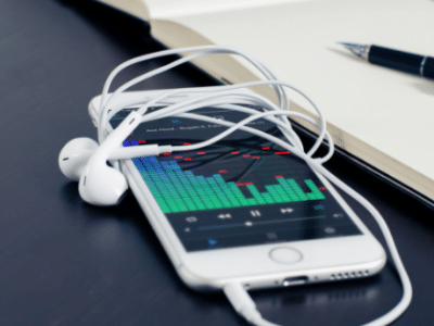 A white phone next to a notebook and earphones.