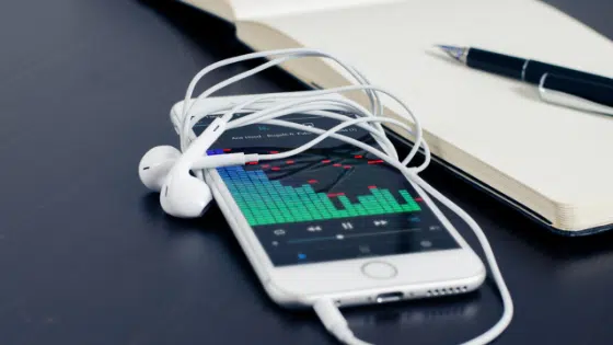 A white phone next to a notebook and earphones.