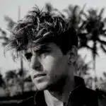 A black and white photo of a man with curly hair.