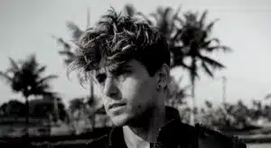 A black and white photo of a man with curly hair.