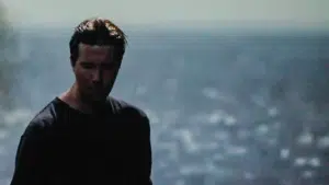 A man in a black shirt standing in front of a city.