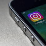 The instagram logo is displayed on an iphone.