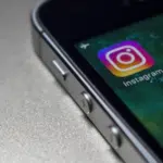 The instagram logo is displayed on an iphone.