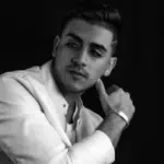 A black and white photo of a man in a white suit.