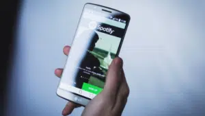 A person holding up a phone with spotify on it.