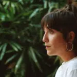 A woman wearing a white shirt and hoop earrings.