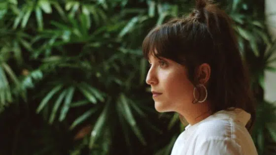 A woman wearing a white shirt and hoop earrings.