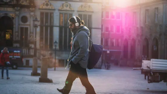 A man walking down a street with headphones on.