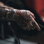 A person with tattoos holding a microphone.