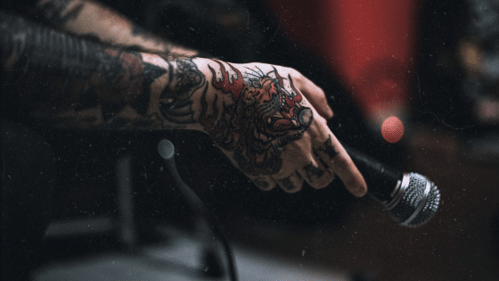 A person with tattoos holding a microphone.
