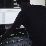 A man working on a mixing desk in a dark room.