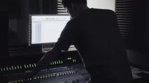 A man working on a mixing desk in a dark room.