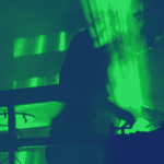 A musician playing a DJ in a dark room with green lights.
