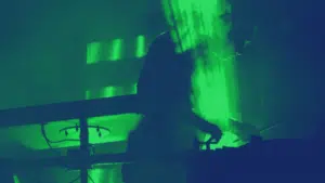 A musician playing a DJ in a dark room with green lights.