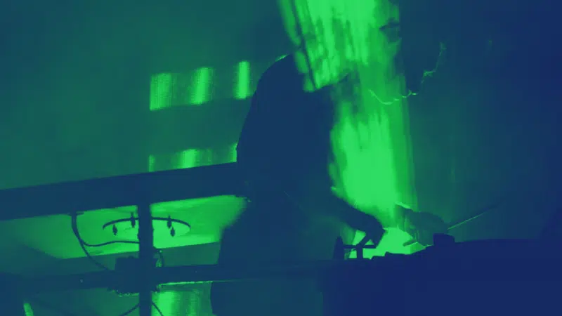 A musician playing a DJ in a dark room with green lights.