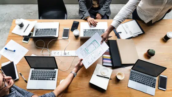 A group of people sitting around a table with laptops.