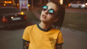 A woman wearing sunglasses and a yellow ringer t - shirt.