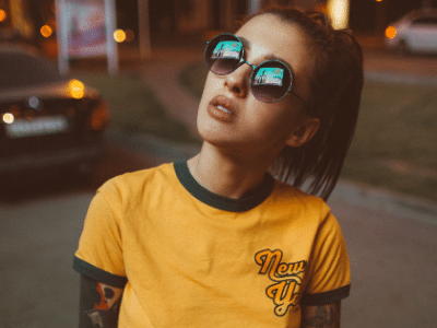 A woman wearing sunglasses and a yellow ringer t - shirt.