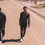 Two men walking down a dirt road in the desert.