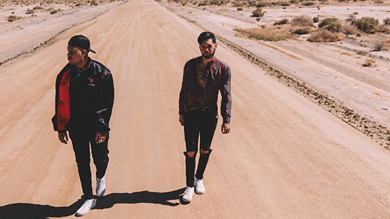 Two men walking down a dirt road in the desert.