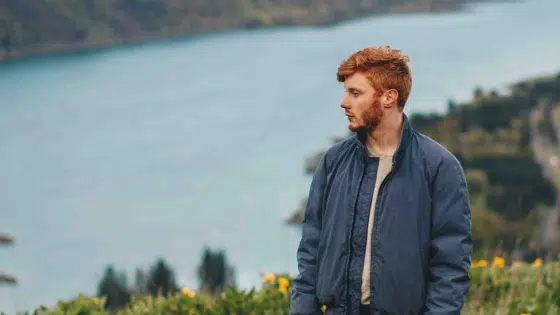 A man standing on a hill overlooking a lake.