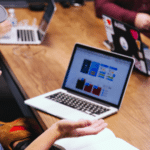 A group of people sitting around a table with laptops.