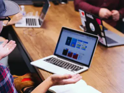 A group of people sitting around a table with laptops.