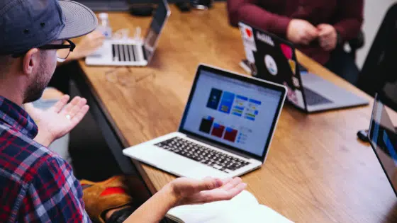 A group of people sitting around a table with laptops.