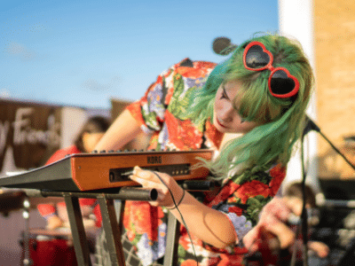 A woman with green hair playing a keyboard.