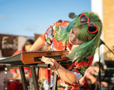 A woman with green hair playing a keyboard.