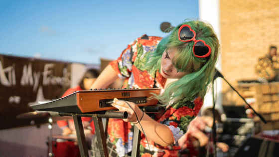 A woman with green hair playing a keyboard.