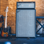 A guitar amp in front of a drum set.