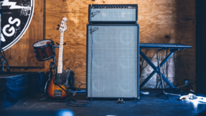 A guitar amp in front of a drum set.