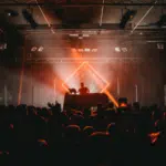 Dj at a concert with a bright light shining on him.