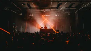 Dj at a concert with a bright light shining on him.