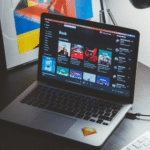 A laptop on a desk next to a monitor.