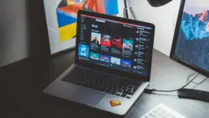 A laptop on a desk next to a monitor.