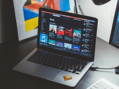 A laptop on a desk next to a monitor.