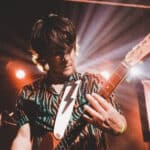 A man playing an electric guitar on stage.