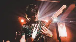 A man playing an electric guitar on stage.