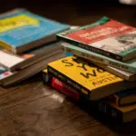 A stack of books on a wooden table.