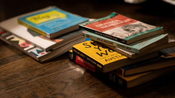 A stack of books on a wooden table.