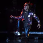 A man in a leather jacket is performing on stage.